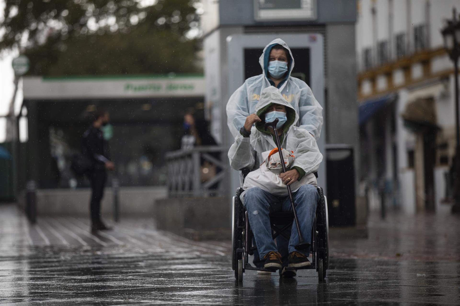 Dos personas con impermeable y mascarillas durante una jornada de lluvia. / Foto: María José López. / Europa Press.