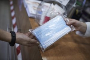 Una farmacéutica enseña a un cliente un paquete de mascarillas en una farmacia. / Foto: Jesús Hellín. / Europa Press.