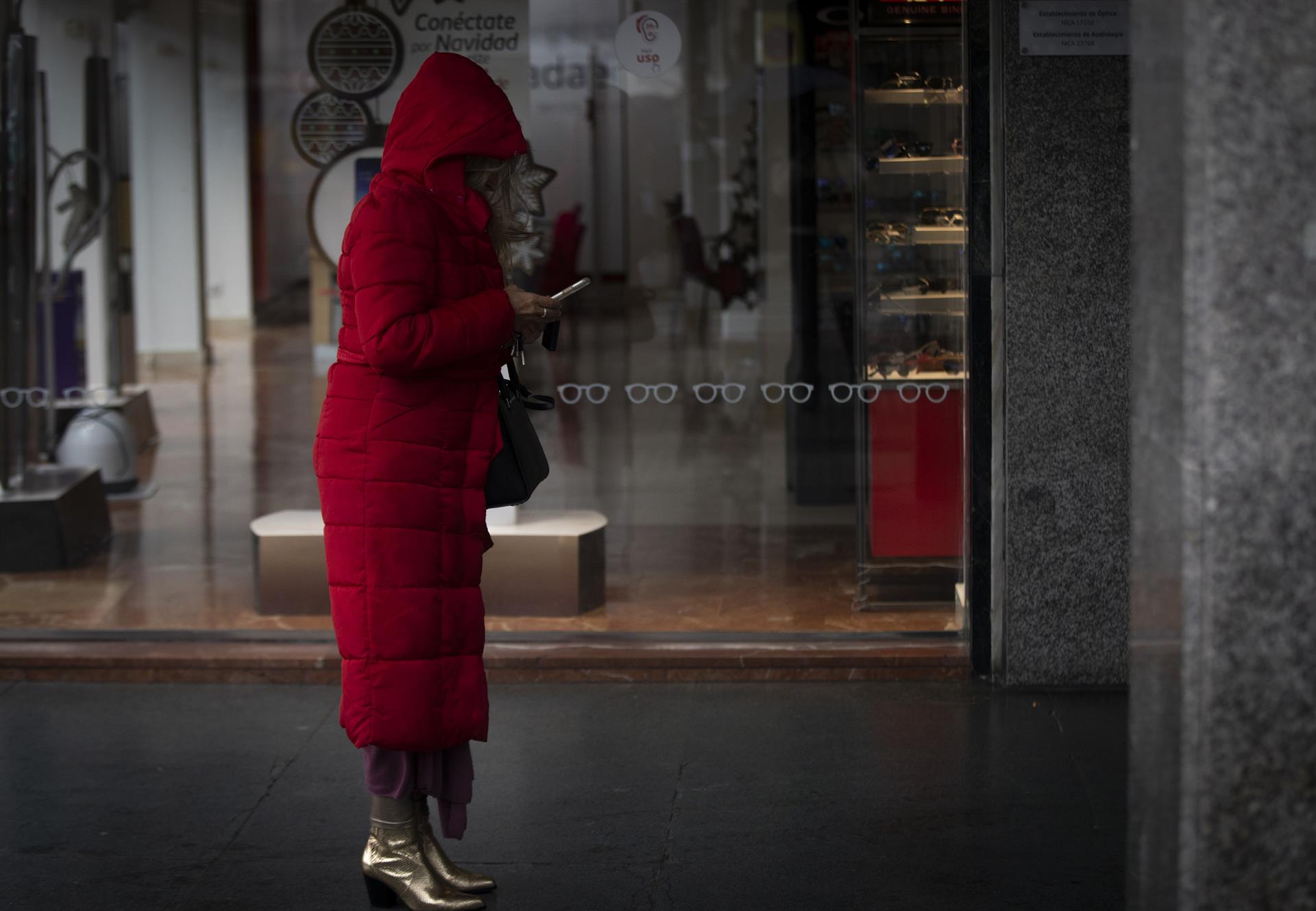 Una mujer bajo un soportal espera que cese la lluvia. / Foto: María José López / Europa Press.